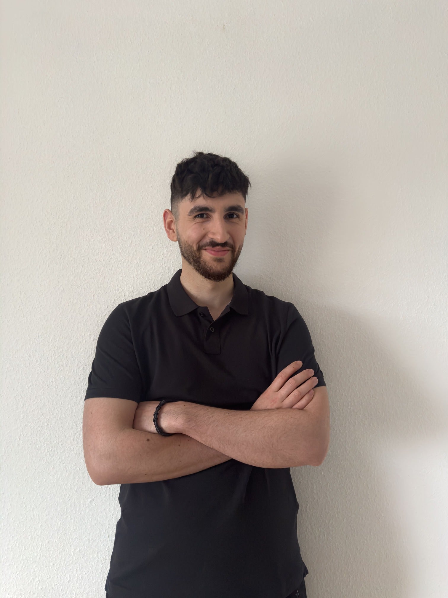Selbstbewusstes Portrait des Movaro-Gründers in schwarzem Polohemd vor heller Wand